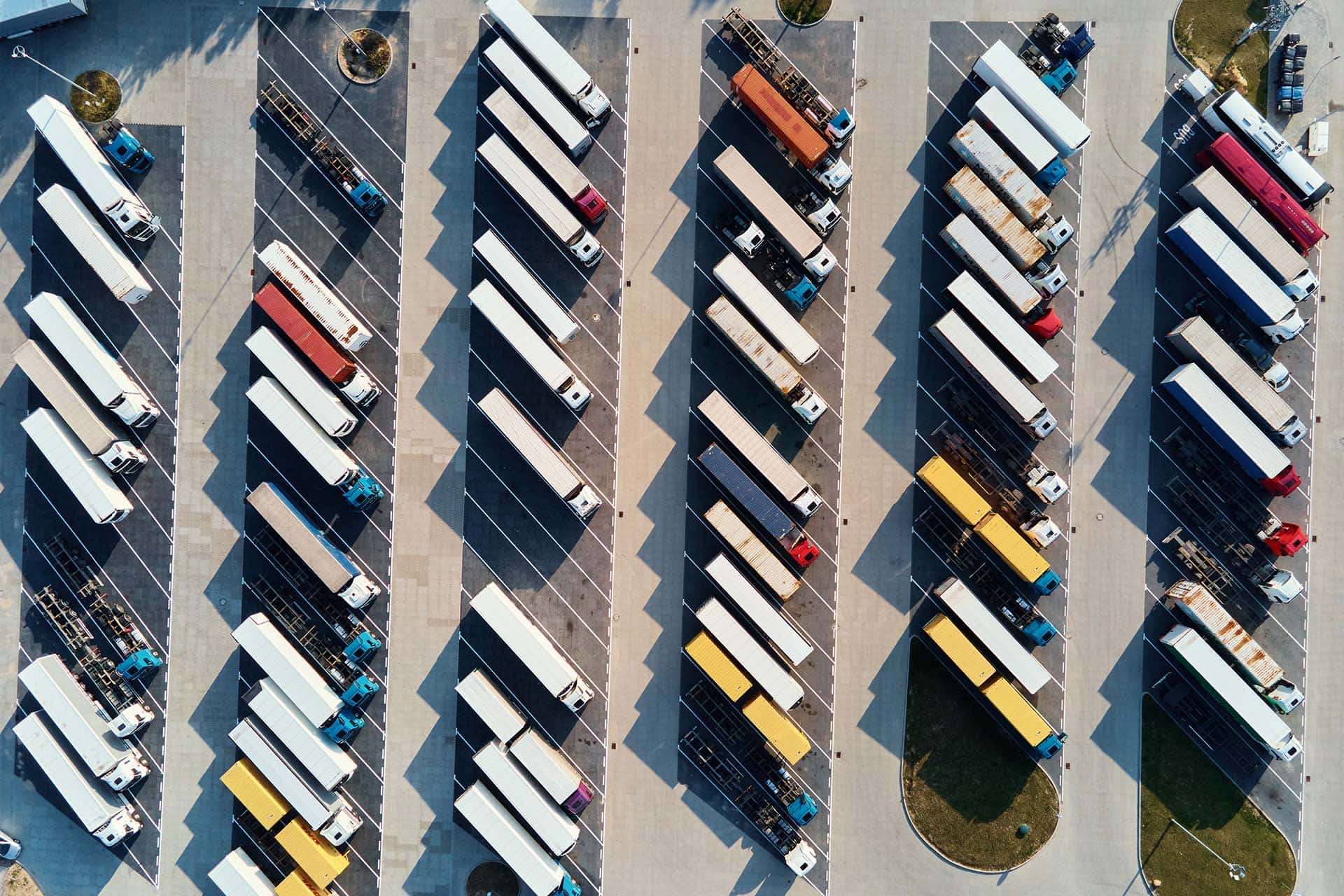 An aerial view of a large fleet yard with rows of trucks and trailers parked by unit